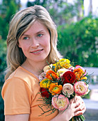 Young woman with a bouquet of Ranunculus (ranunculus) and Vaccinium (vaccinium)