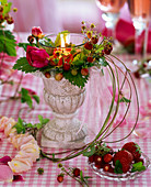 Kranz aus Fragaria (Walderdbeeren) und Rosa (Rosen) um Kerzenglas