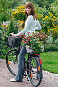 Junge Frau hat mit dem Fahrrad Pflanzen eingekauft