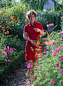 Frau kommt mit frisch geschnittenen Blumen aus dem Bauerngarten