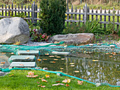 Teich im Herbst mit Netz abgedeckt zum Schutz vor Laub