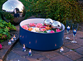 Blossoms of Rosa (roses) in tub with water, decorative balls, floating candles