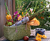 Bouquet of Gladiolus (gladioli), Malus (apples), newspaper in wicker basket