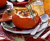 Pumpkin soup in cucurbita (pumpkin) decorated with allium (chives)