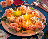 Blüten von Rosa (Rosen), Kerzen in Herz - Form auf rosa