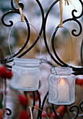 Screw glasses as lanterns with frost optic spray hanging on a metal fence