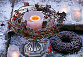 Wreath of clematis branches, rose hips, Hedera (ivy) around a bowl with a lantern