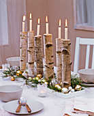 Weihnachtliche Tischdekoration mit Ästen von Betula (Birke) als Kerzenhalter