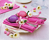Tischdekoration mit Primula (Primeln) auf rosa gefalteten Servietten