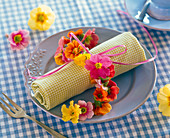 Necklace of primula on checkered rolled napkin
