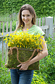 Woman with Ranunculus acris (buttercup) in moss bag