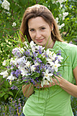 Woman with bouquet of Aquilegia (columbine), Nepeta (catmint)