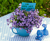 Bouquet of Myosotis (forget-me-not) in cup, sign '...a nice week'.