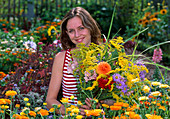 Junge Frau pflückt Blumenstrauß in Bauerngarten