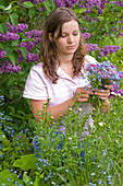 Woman picking bouquet of Myosotis and Dicentra