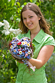 Woman with bouquet of Myosotis (forget-me-not), Bellis