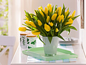 Tulipa (Tulpen) in Glasvase auf Holz-Tablett