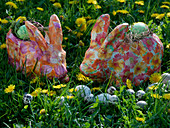 Colourful papier-mâché Easter bunnies in meadow with Taraxacum (dandelion)