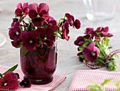 Viola wittrockiana (Pansy) in red glass vase