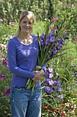 Young woman with a bouquet of violet gladioli (gladiolus)