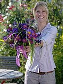 Young woman with bouquet of callistephus (summer aster), Erigeron