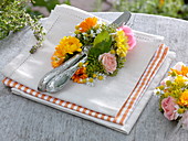 Cutlery in a flower wreath made of marigold, roses and chamomile