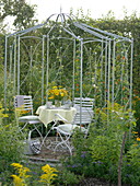 Round metal pavilion on small round terrace in natural garden