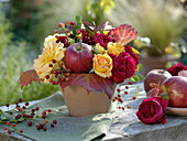 Small autumn bouquet with roses, leaves and apple