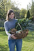 Young woman holding wicker basket with vegetables