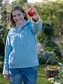 Junge Frau hält einem Apfel in der Hand
