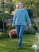 Young woman carrying a wicker basket with apples