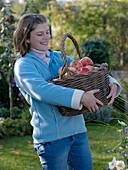 Junge Frau hält einen Weidenkorb mit Äpfeln