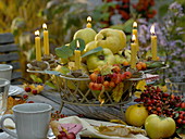 Metal basket with metal florets as candle holders filled with quinces