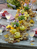 Tischdeko mit Quitten auf Blätterteppich