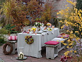 Herbstlich gedeckter Tisch mit Sträussen aus Rosen und Chrysanthemen