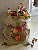 Basket with apples (Malus) and oranges (Citrus sinensis) in a jute bag