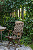Holz-Stuhl auf kleiner, gepflasterter Terrasse vor Gartenhaus