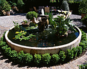 Ein steinerner Elefantenbrunnen in einem kreisrunden Becken im gepflasterten Innenhof