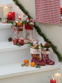 Children's rubber boots as Father Christmas boots placed on stairs and decorated