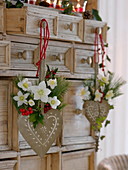 Small bouquets of Helleborus and Ilex in heart vases to hang