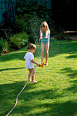HAZEL AND WILLIAM PLAYING with A HOSEPIPE IN THE GARDEN. THE NICHOLS Garden, READING