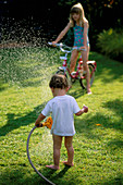 HAZEL AND WILLIAM PLAYING with A HOSEPIPE IN THE GARDEN. THE NICHOLS Garden, READING