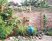 GRAVEL COURTYARD with Water Feature: BRICK WALL, TRELLIS, Water SPOUT , TURQUOISE Container, ROCKS AND CLEMATIS Montana