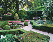 Privatgarten mit Buchsbaumhecke, beschnittenen Stechpalmen, Beetbegonien, Teich und Amorwasserbrunnen, Steinurne und Holzbank