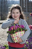 Girl with Primula acaulis (primroses) in wicker bag