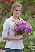 Young woman with bouquet of Geranium (cranesbill), Dianthus (carnations)