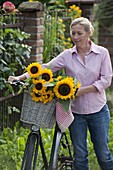 Frau mit Fahrrad und Sonnenblumen
