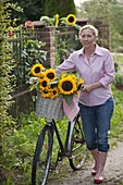 Frau mit Fahrrad und Sonnenblumen