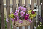 Tasche mit Sommerblumen als Willkommensgruß an Gartentor gehängt