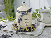Keramikdose mit Kamillen-Lavendel-Tee, dekoriert mit Blüten und Kranz